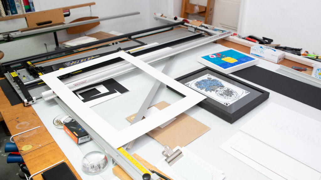A work table with photo frames and mounts being assembled lay across.